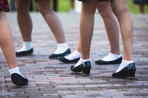 Young women wearing vintage polka dot dresses dancing in city park, close up view of same black dancing shoes and white socks, female retro jazz swing dances, dance lessons © tsuguliev