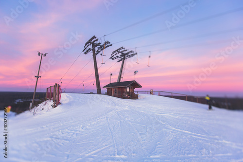 Beautiful cold mountain view of ski resort, sunny winter day with slope, piste and ski lift, with group of mountain downhill skiers and snowboarders