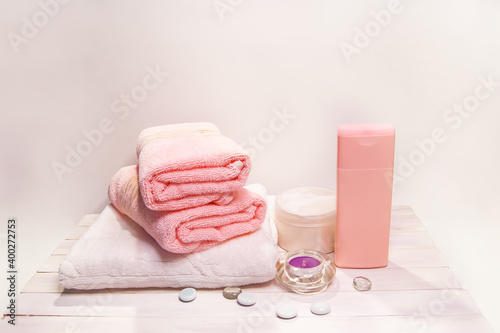 Spa still life - a flowers and towels on a wooden stand. White background. Beige, pink and white tones.
