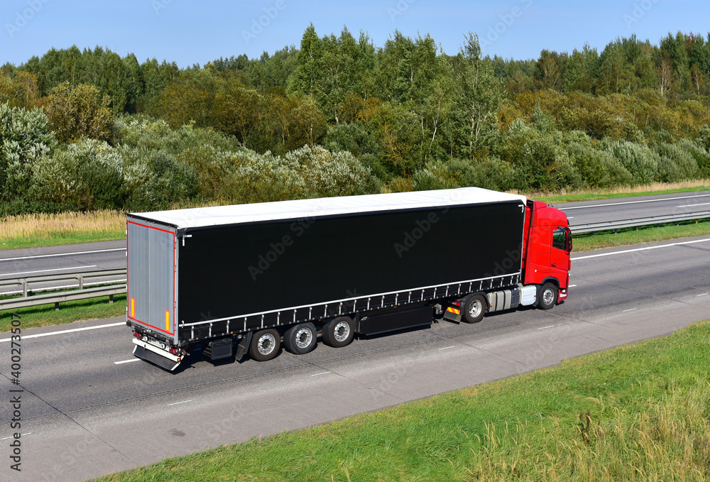 Truck with semi-trailer driving along highway on the sunset background. Goods delivery by roads. Services and Transport logistics. Soft focus. Truck with semi-trailer driving along highway on the sunset background. Goods delivery by roads. Services and Transport logistics. Soft focus.