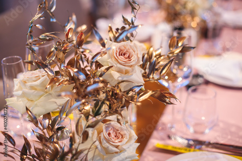 Beautiful wedding ceremony interior and table decor  flower decoration with flowers bouquet  with roses  tulips  peonies in pink and golden color tones