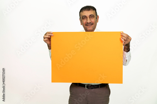 Man holding an orange banner in his hand. It can be written on. She is dressed in a white shirt and fabric pants. Isolated image white background.