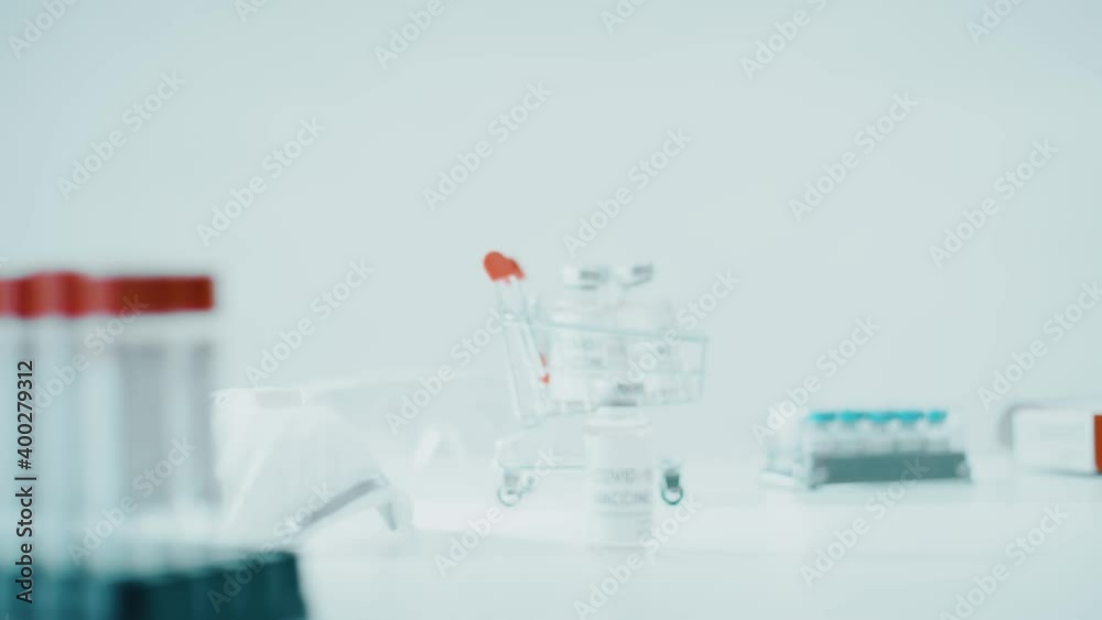 Small shopping cart with COVID-19 vaccine vials. Vaccination and research concepts Small shopping cart with COVID-19 vaccine vials. Vaccination and research concepts