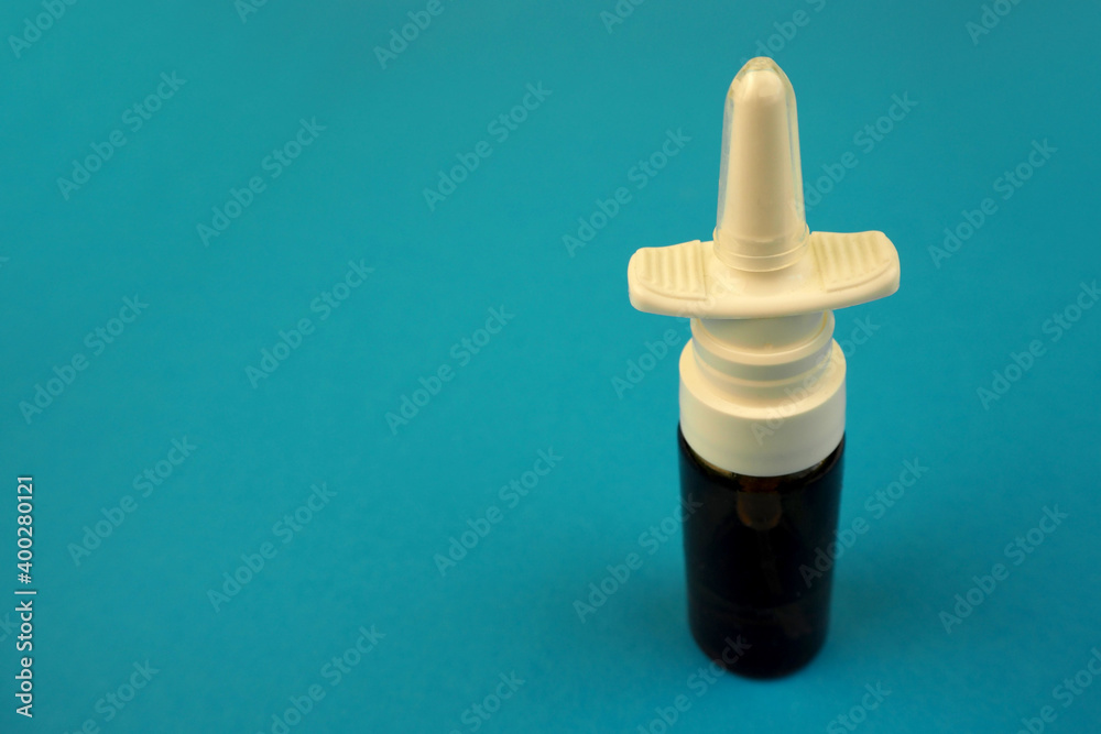nose spray in a glass container and a white plastic cap side view on a blue background nose spray in a glass container and a white plastic cap side view on a blue background