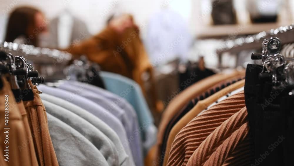 Women's clothing hangs on hangers inside the store. Woman choose things. Women's clothing hangs on hangers inside the store. Woman choose things.