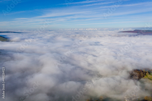 Aerial view of mountains poking through a sea of fog and low cloud in a rural setting © whitcomberd