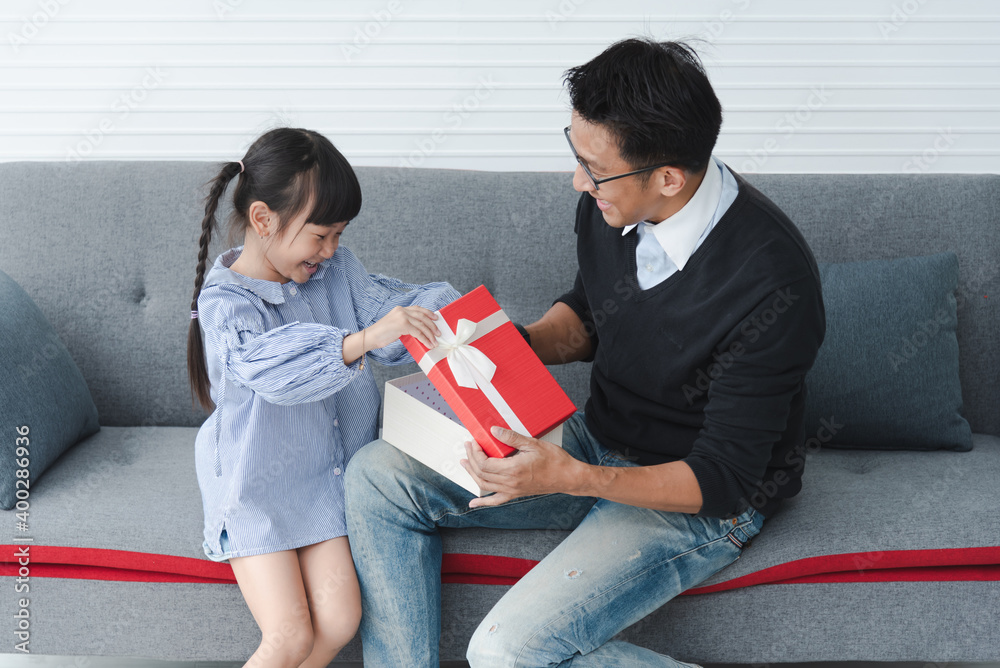 Celebrate father days. Little girl is giving her father a gift box. Children daughters congratulating dad and giving him gift box. Family holidays. happy family asia. Celebrate father days. Little girl is giving her father a gift box. Children daughters congratulating dad and giving him gift box. Family holidays. happy family asia.