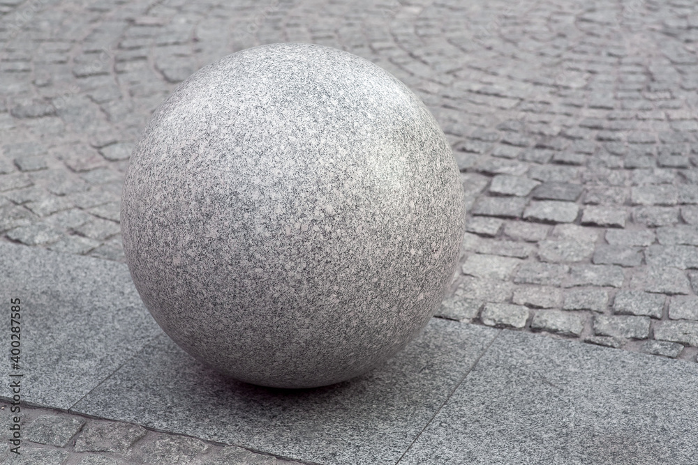 Naklejka granite ball on the pedestrian sidewalk paved with stone tiles, cityscape urban street architecture, nobody.