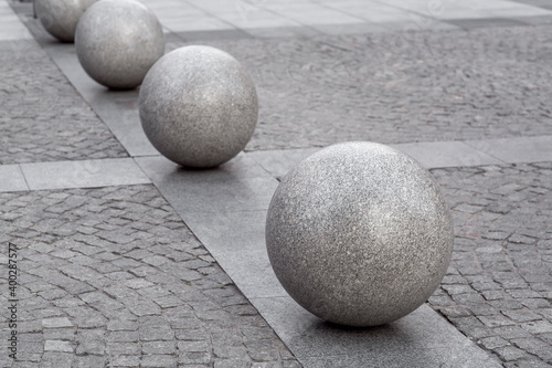 row of granite balls on the pedestrian sidewalk paved with stone tiles  cityscape urban street architecture  nobody.