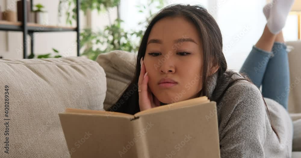 Woman lying on sofa and reading a book at home Woman lying on sofa and reading a book at home