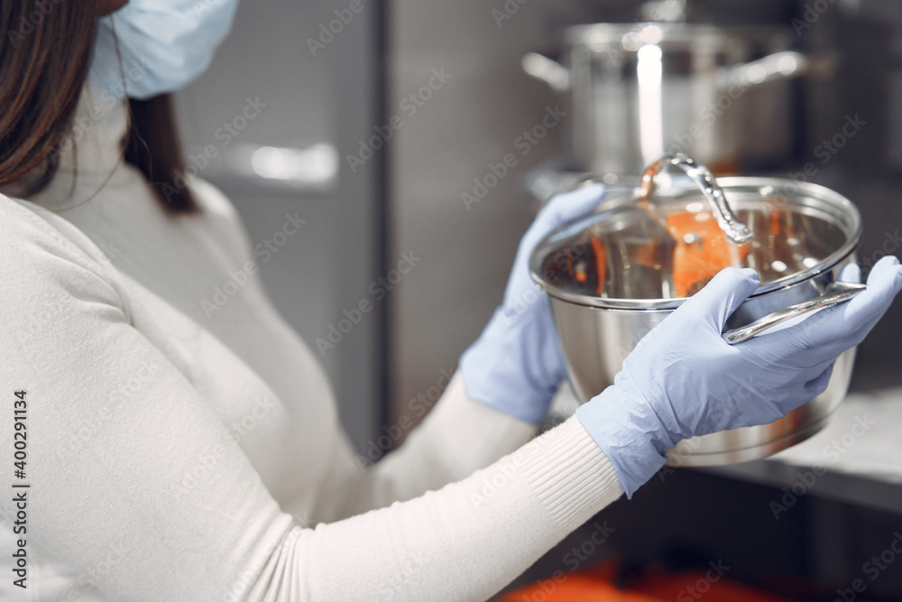 Woman examines various items of dishes. Beautiful woman shopping tableware in supermarket. Corona virus concept.