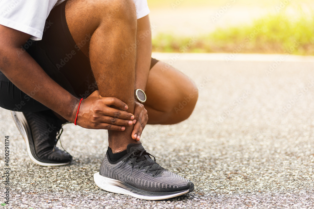Close up Asian young sport runner black man wear watch hands joint hold leg pain because of twisted ankle broken while running at the outdoor street health park, healthy exercise Injury from workout - obrazy, fototapety, plakaty 