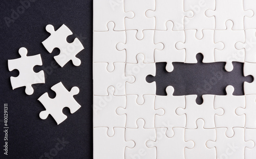 Top view flat lay of paper plain white jigsaw puzzle game texture last pieces for solve and place, studio shot on a black background, quiz calculation concept photo