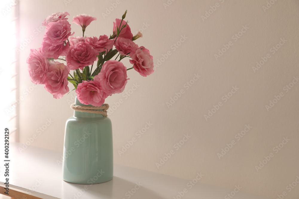 Obraz premium Bouquet of beautiful Eustoma flowers on table near light wall. Space for text