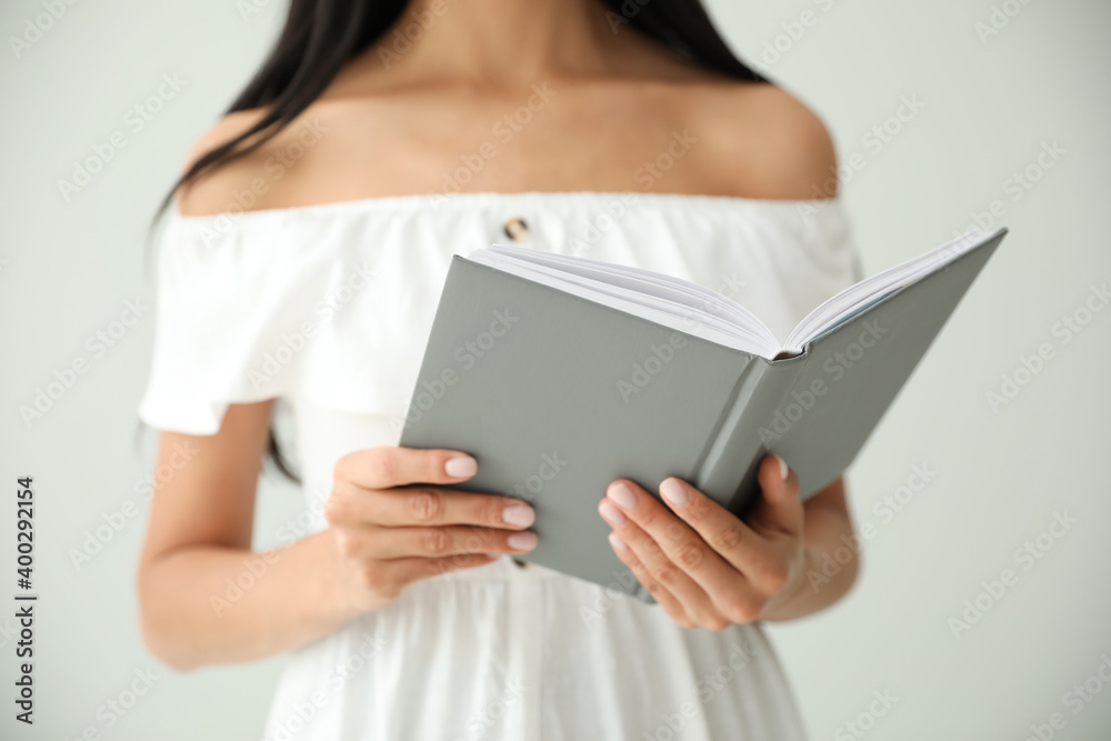 Young woman reading book on light grey background, closeup Young woman reading book on light grey background, closeup
