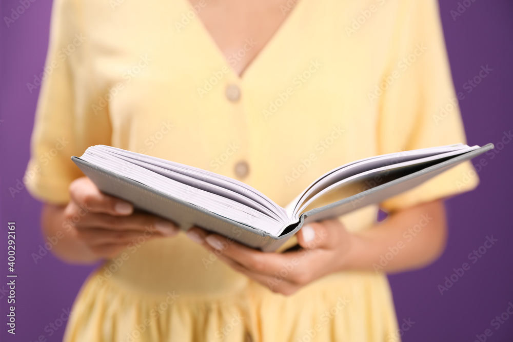 Young woman with book on purple background, closeup Young woman with book on purple background, closeup