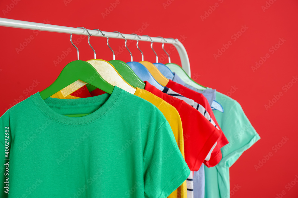 Obraz premium Rack with stylish children clothes on red background, closeup