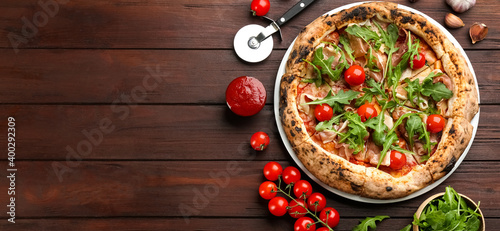 Tasty pizza with meat and arugula on wooden table, flat lay. Space for text