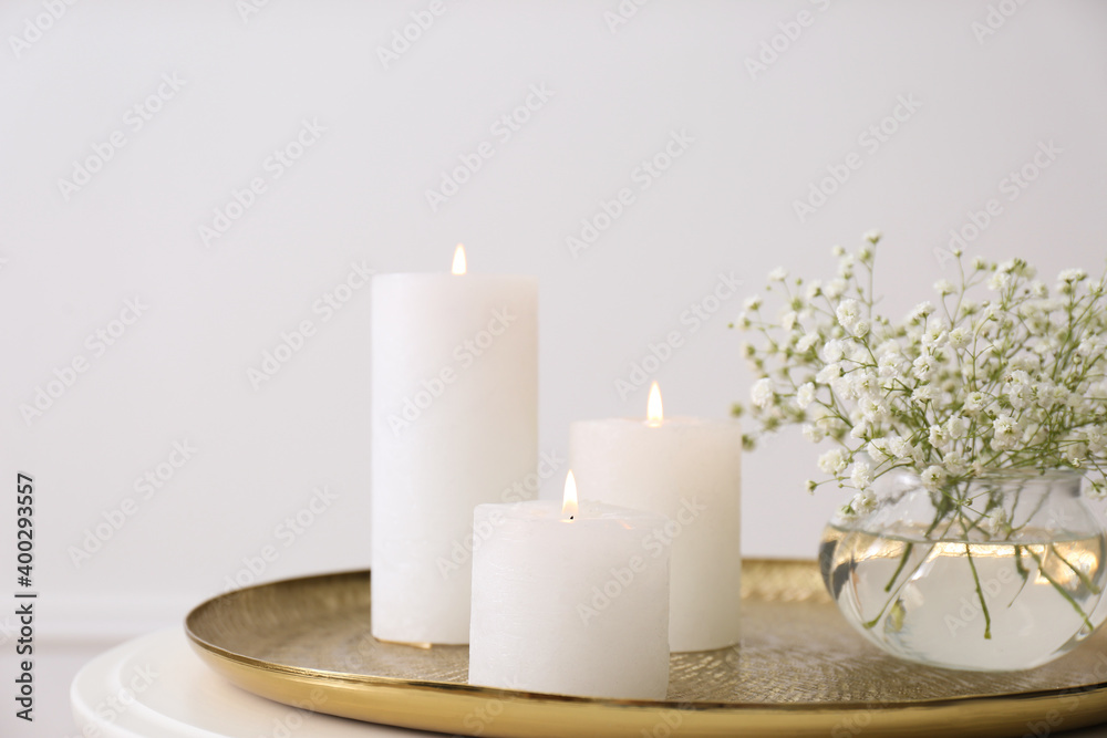 Vase with beautiful flowers and burning candles on table indoors, closeup. Interior elements Vase with beautiful flowers and burning candles on table indoors, closeup. Interior elements
