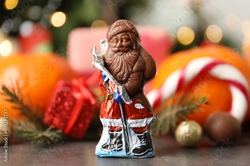 Fototapeta Naklejka Na Ścianę i Meble -  Chocolate Santa Claus candy against Christmas decorations, sweets and tangerine fruits