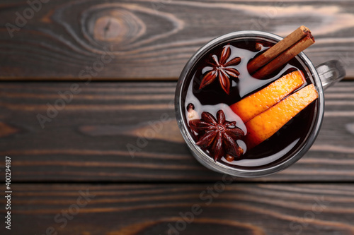 Aromatic mulled wine on wooden table, top view. Space for text