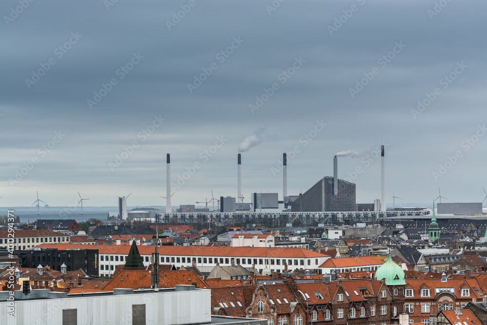 Aerial view of old downtown of Copenhagen City from the The Round Tower (Rundetaarn) in rainy misty day with cloudy sky with red house roofs and factories