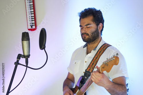 musician with electric guitar playing music in studio