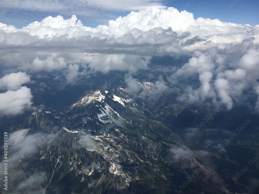 Watching weather from above cloud view of snow covered mountain range as a world traveler daydreams about the landscape they just hiked.