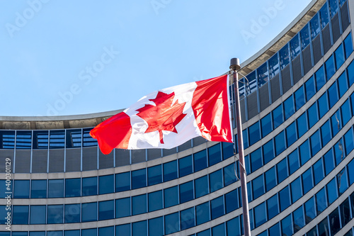 Photography Waving Canadian flag with Toronto city hall building in background in downtown Toronto