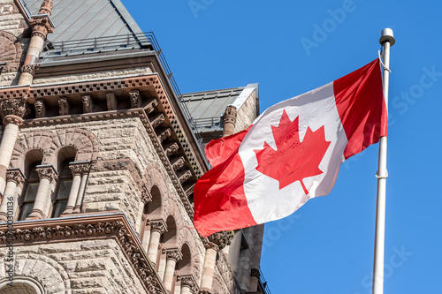 Photography The waving Canadian flag with Old City Hall in background in Toronto, Canada