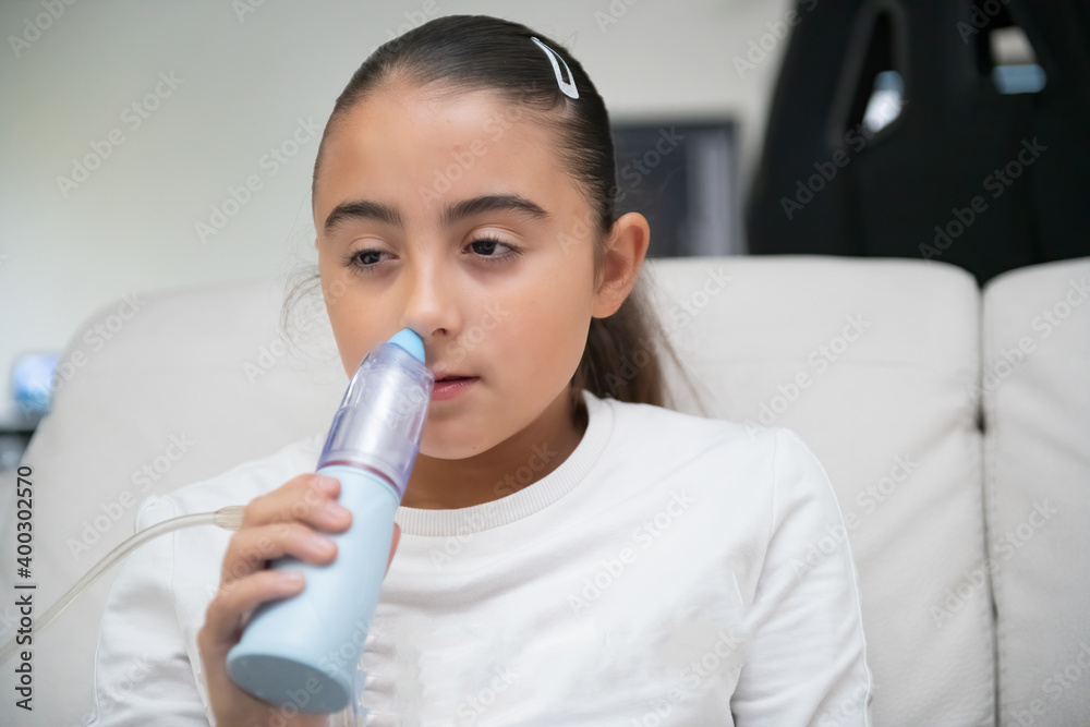 Young girl holding aerosol inhalator at home Young girl holding aerosol inhalator at home