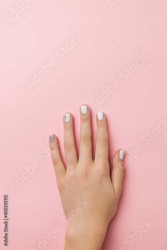 A woman's hand with a stylish light makeup on a pink background.