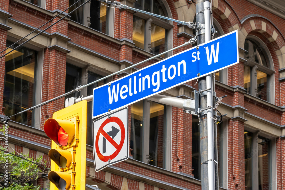 Toronto, Canada - October 24, 2019: Sign of Wellington street sign with traffic light in downtown Toronto Canada. Wellington Street is one-way westbound street north of Front Street in Toronto. Toronto, Canada - October 24, 2019: Sign of Wellington street sign with traffic light in downtown Toronto Canada. Wellington Street is one-way westbound street north of Front Street in Toronto.
