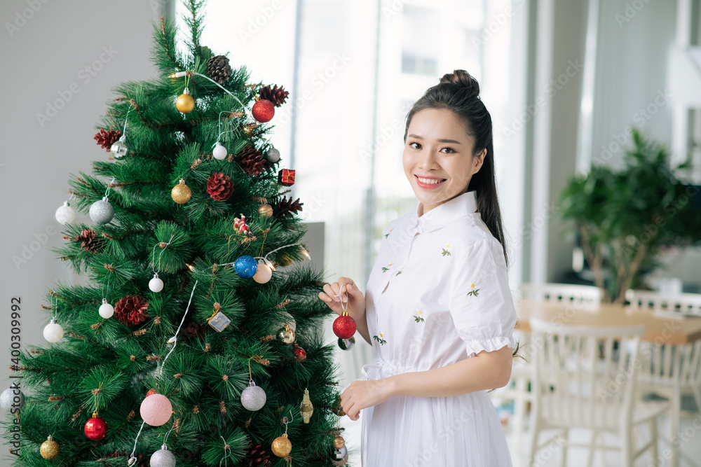 Portrait of happy young woman decorating christmas tree with christmas ball Portrait of happy young woman decorating christmas tree with christmas ball