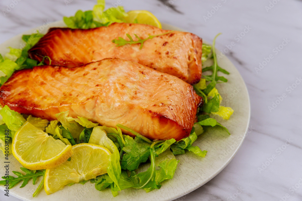 Baked salmon fillet with green salad on gray plate. Baked salmon fillet with green salad on gray plate.
