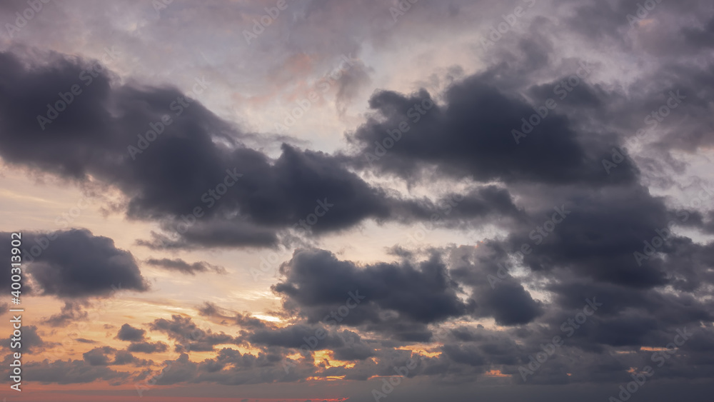 Obraz premium Disturbing sunset sky. Dusk. Dark clouds float, through which orange sunlight breaks through.