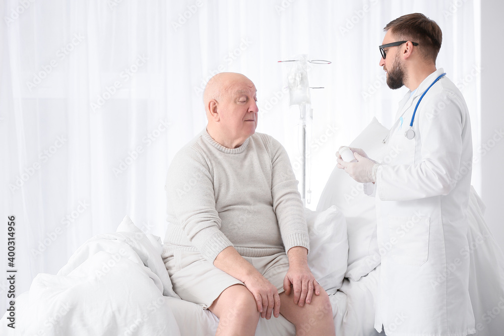 Doctor giving medicine to senior man in clinic. Prostate cancer awareness concept Doctor giving medicine to senior man in clinic. Prostate cancer awareness concept