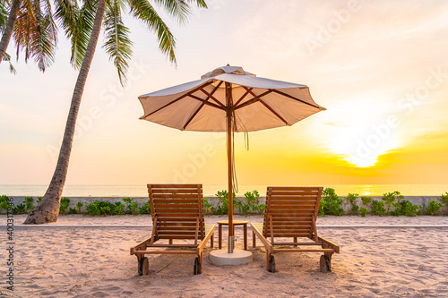 Fototapeta Naklejka Na Ścianę i Meble -  Umbrella and deck chair on tropical beach sea ocean at sunset or sunrise time