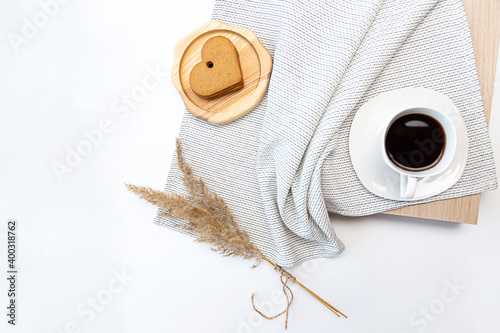 Minimalistic flat lay with pampas grass, cup of coffee and heart shaped gingerbread cookies on white table with place for text.