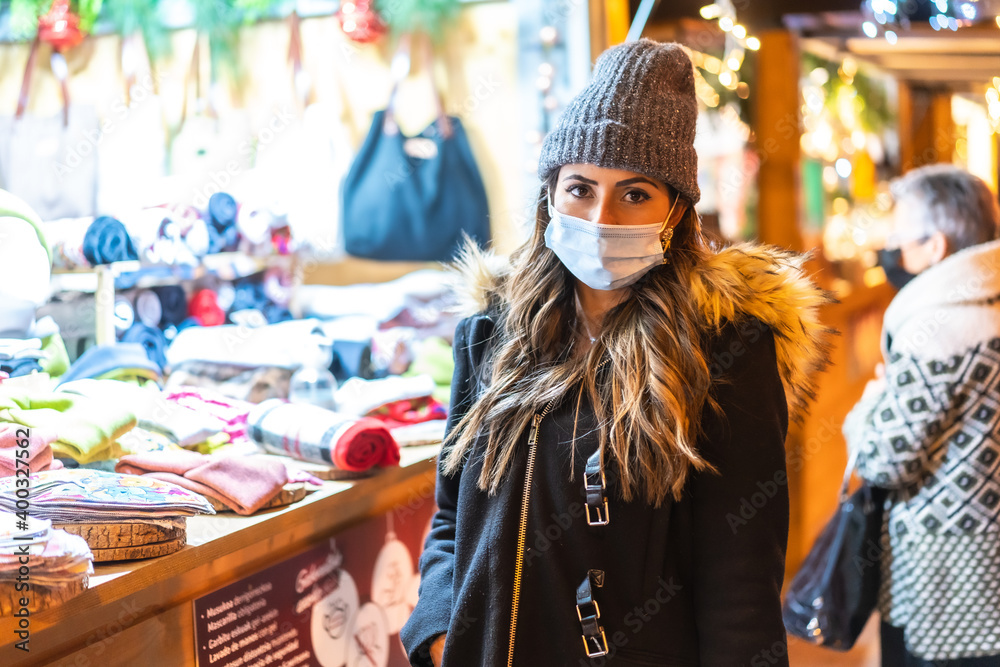 Christmas lifestyle in a new normal. Young girl with face mask visiting the Christmas market in the coronavirus pandemic, covid-19