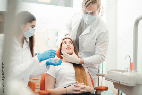 Dentists in white coats and gloves prepare for a procedure for a client