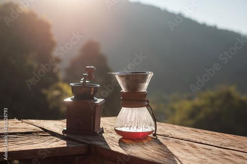 Hot arabica coffee and Vintage coffee drip equipment on wooden table in the morning with mountain and nature background