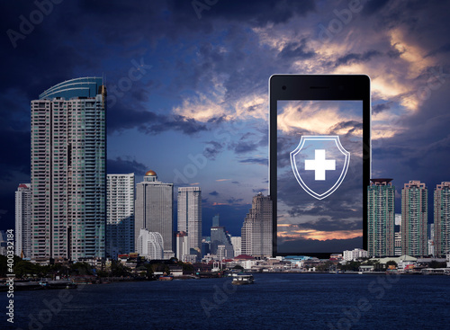 Photography Cross shape with shield flat icon on modern smart mobile phone screen over offic