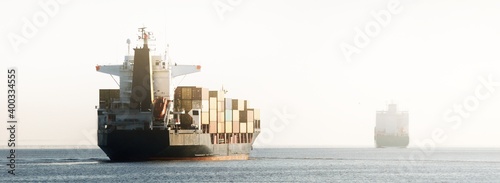 Foto Large cargo container ship leaving the port, sailing in a still sea water