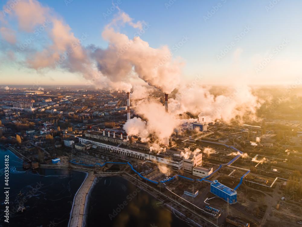 Air pollution by Factory chimneys producing smoke at sunrise, aerial view. Environment and ecology crisis, climate change, global warming
