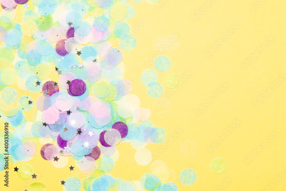 Blue, green, purple, pink and yellow paper confetti on a vibrant yellow background