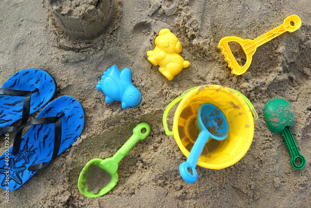 Summer concept on a sandy beach, bucket, spade and blue sandals Summer concept on a sandy beach, bucket, spade and blue sandals