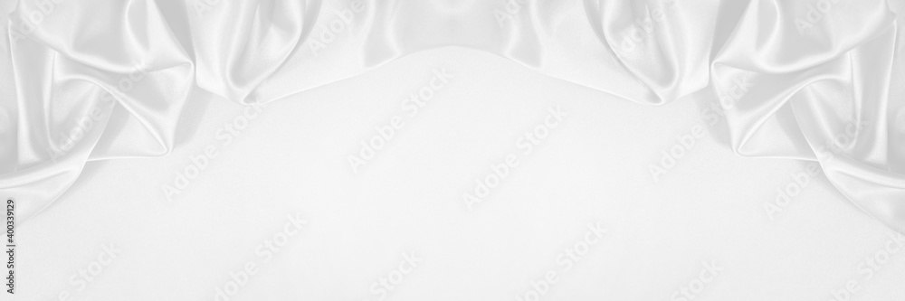 White abstract festive elegant background. Beautiful drapery of soft folds of fabric. Border. Luxurious silk satin background with copy space for your design. Wide banner. Wedding, anniversary concept