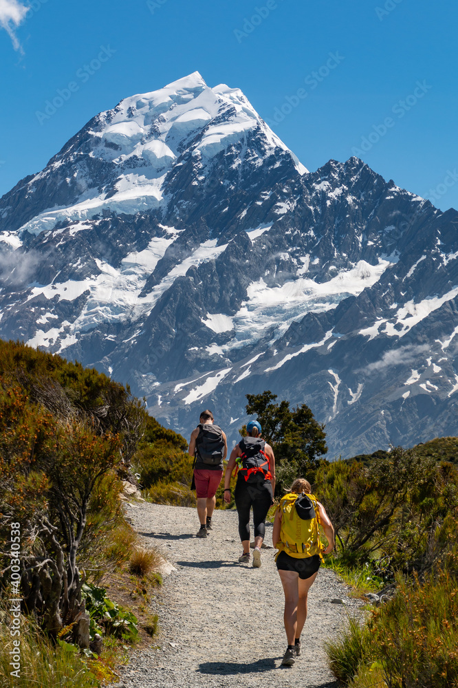 three hikers walking towards a mountain
