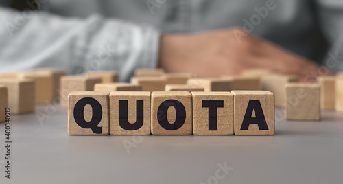 The word QUOTA made from wooden cubes. Shallow depth of field on the cubes